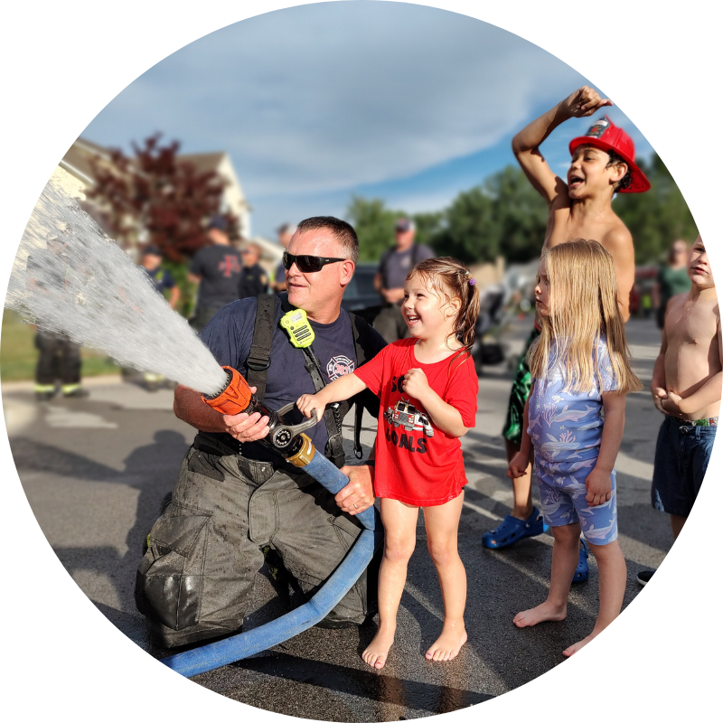 firefighter spraying hose with kids