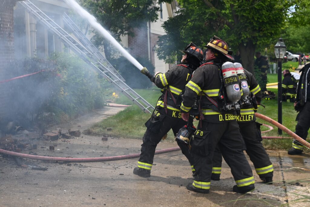 fire fighters with hose fighting structure fire